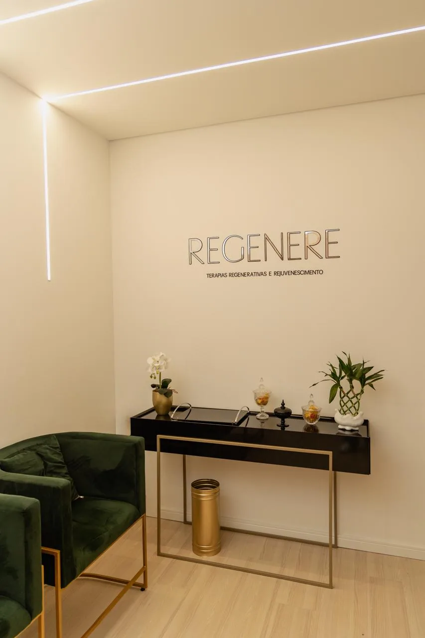 Recepção do REGENERE, com poltronas verdes, aparador preto e a marca REGENERE na parede